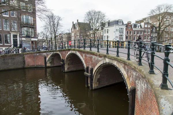 AMSTERDAM, PAÍSES BAJOS 31 DE MARZO DE 2016. Típica vista urbana. Una hilera de arquitectura tradicional en el terraplén del canal y el puente viejo — Foto de Stock