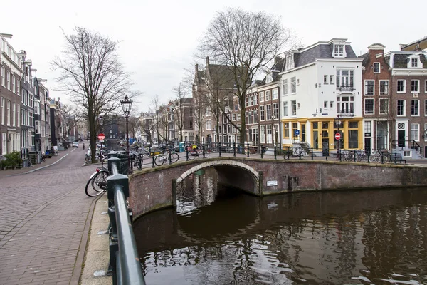 Amsterdam, Nizozemsko na 31 březnu 2016. Typický městský pohled. Starý most přes kanál, kanál a budovy stavby Xvii a Xviii na nábřežích. — Stock fotografie