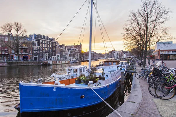 Amsterdam, Nizozemsko na 31 březnu 2016. Typický městský pohled při západu slunce. Řeky Amstel a budovy stavby Xvii a Xviii na náspy. Lodě kotví u banky — Stock fotografie