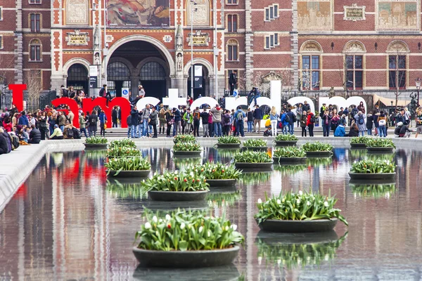 Amsterdam, Holandia, 31 marca 2016 r. Plac Museumplein. Rijksmuseum. Turyści mają dobry czas w pobliżu napis I Amsterdam. Fontanna ozdobiona doniczki z tulipany — Zdjęcie stockowe