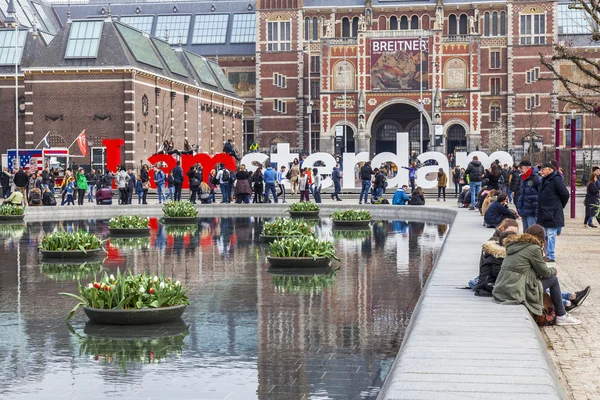 AMSTERDAM, NETHERLANDS on March 31, 2016. Площадь Музея. Музей Рийгикогу. Туристы хорошо проводят время рядом с надписью I AMsterdam. Фонтан украшен цветочными горшками с тюльпанами — стоковое фото