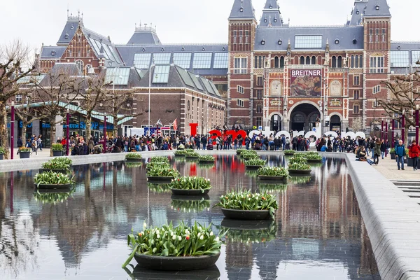 AMSTERDAM, PAYS-BAS, le 31 mars 2016. Museum Square. Rijksmuseum. Les touristes passent un bon moment près de l'inscription I AMsterdam. La fontaine décorée de pots de fleurs avec des tulipes — Photo