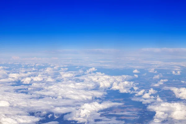 Göksel manzara. Güneşin uçan uçak penceresinden ile beyaz bulutlar ve karasal yüzey görünümünü yaktı — Stok fotoğraf