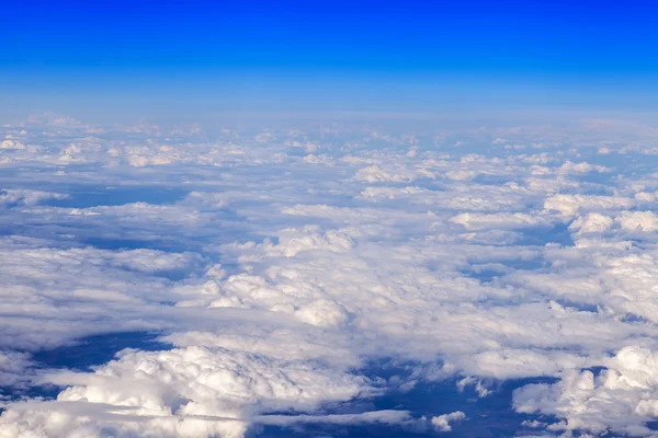 Paysage céleste. Vue des nuages blancs et de la surface terrestre éclairée par le soleil depuis une fenêtre de l'avion volant — Photo