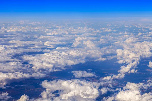 天の風景です。空飛ぶ飛行機の窓から太陽と白い雲と地上の表面の表示点灯 — ストック写真
