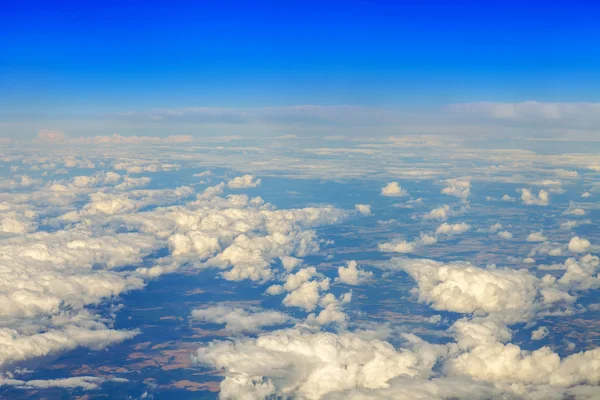 天の風景です。空飛ぶ飛行機の窓から太陽と白い雲と地上の表面の表示点灯 — ストック写真