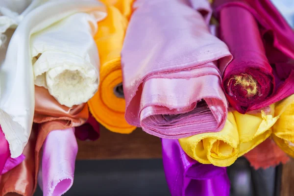 Rolls of multi-colored fine fabrics on a counter of shop — Stock Photo, Image