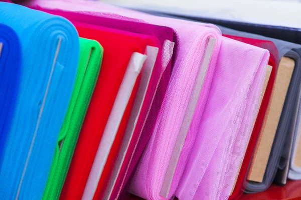 Rolls of multi-colored fine fabrics on a counter of shop — Stock Photo, Image