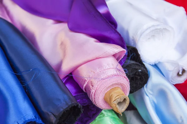 Rolls of multi-colored fine fabrics on a counter of shop — Stock Photo, Image