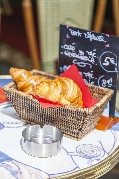 Lekkere croissants in een mandje op een tafeltje in café — Stockfoto