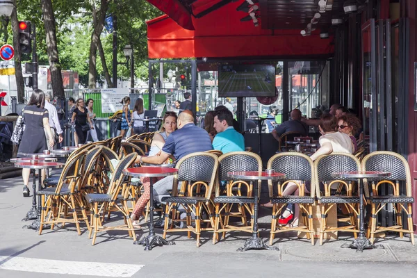 Paris, Frankreich, am 8. Juli 2016. Kleine Tische eines typischen Pariser Cafés auf dem Bürgersteig. Menschen essen und erholen sich. — Stockfoto