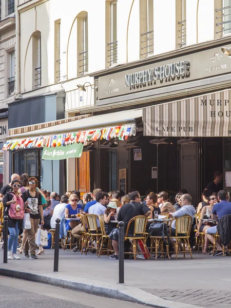 Paris, Frankreich, am 8. Juli 2016. Kleine Tische eines typischen Pariser Cafés auf dem Bürgersteig. Menschen essen und erholen sich. — Stockfoto