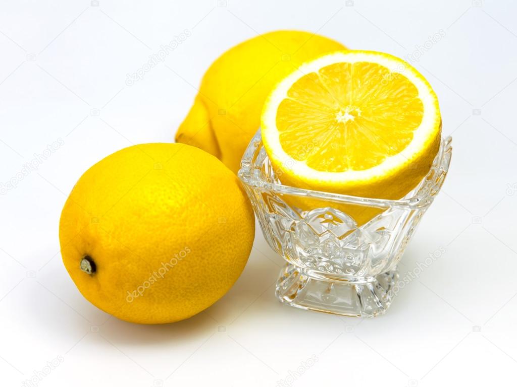 lemons and a half of a lemon in a transparent ice-cream bowl