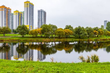 Saint Petersburg, Rusya, 13 Ekim 2020. Sonbahar manzarası. Çok katlı modern binalar ve portakal ağaçları göletin sularını yansıtıyor.
