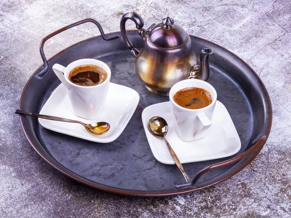 Two white porcelain cups of espresso coffee on a metal vintage platter