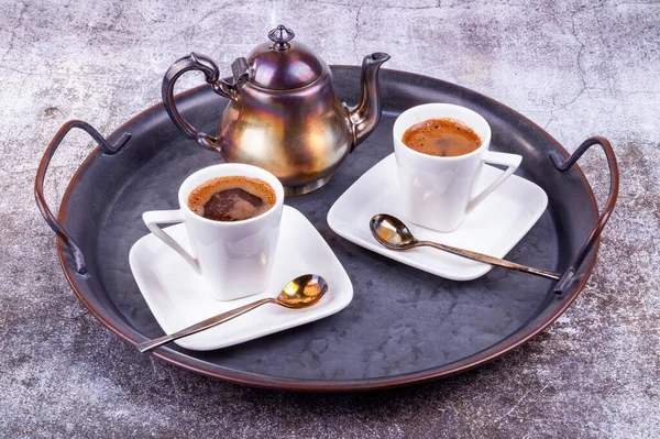 Two white porcelain cups of espresso coffee on a metal vintage platter