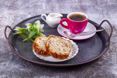 Pembe porselen bardakta espresso kahve, portakal sürahisinde krema ve klasik metal tepside kek.