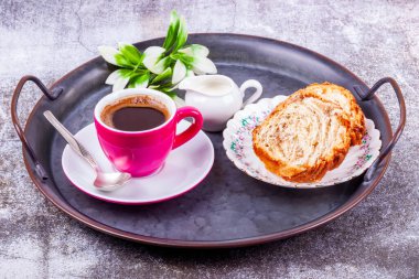 Pembe porselen bardakta espresso kahve, portakal sürahisinde krema ve klasik metal tepside kek.