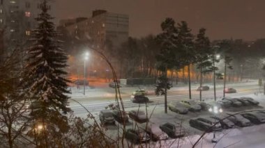Pushkino, Rusya, 2 Ocak 2021. Karla kaplı bir caddenin penceresinden ve yerleşim alanındaki bir otoparktan görüntü. Kar yağıyor. Gece vakti.
