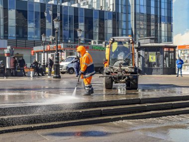 Moskova, Rusya, 25 Mart 2021. Bir hademe caddeyi temizler, kaldırımı hortumla suyla yıkar..