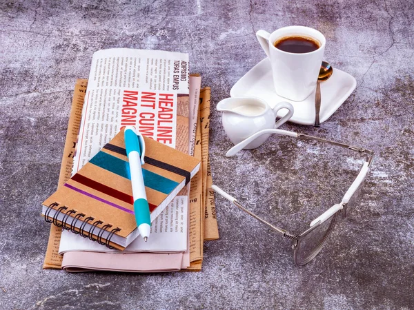 Vintage newspaper and white porcelain coffee cup on the table in a cafe