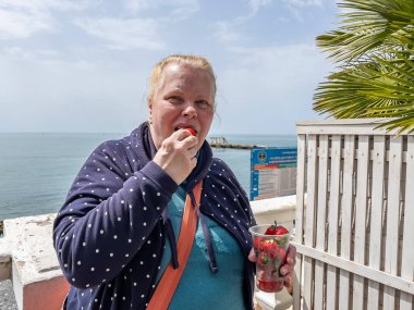 Sochi, Rusya, 18 Nisan 2021. Yaşlı bir kadın güneşli bir bahar gününde sette çilek yer..