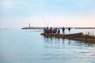 Deniz yüzeyindeki resimler ve uzaktaki balıkçılar.