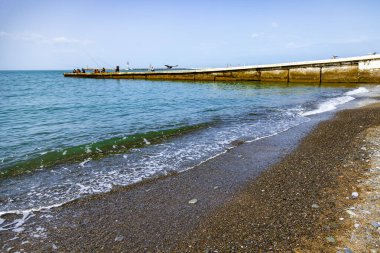 İnsanlar uzaktaki iskeleden balık yakalıyor.