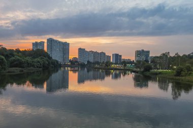Pushkino, Rusya, 29 Ağustos 2021. Serebryanka nehrinin kıyısındaki yeni çok katlı evler ve onun yansıması. Gün batımı zamanı