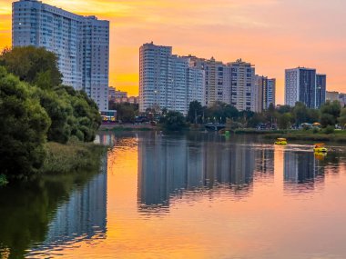 Pushkino, Rusya, 29 Ağustos 2021. Serebryanka nehrinin kıyısındaki yeni çok katlı evler ve onun yansıması. Gün batımı zamanı