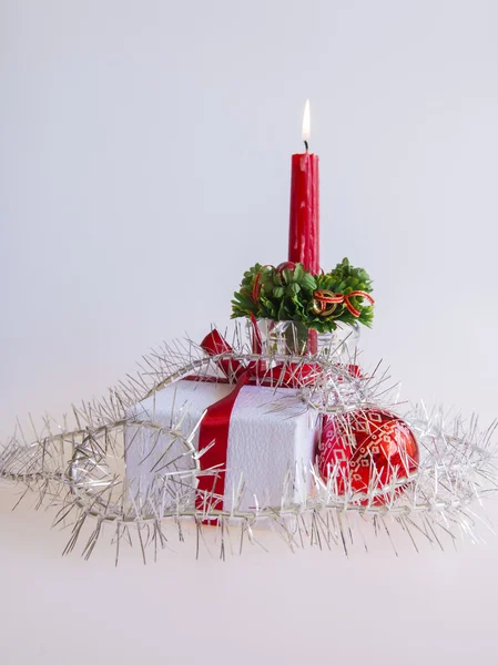 Neujahrsgeschenk in einem weißen Karton, Schmuck für einen Tannenbaum und eine brennende Kerze — Stockfoto