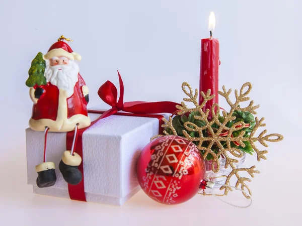 Cadeau du Nouvel An dans une boîte en carton blanc, bijoux pour sapin et bougie allumée — Photo