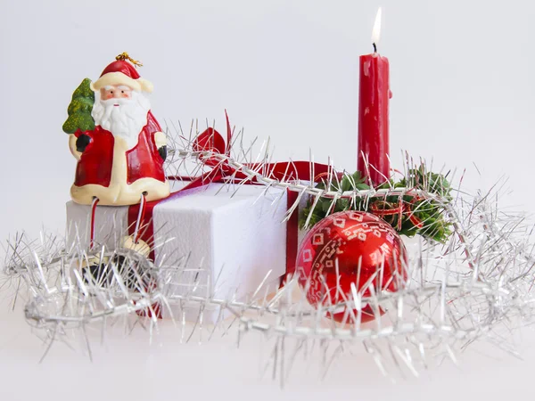Il regalo di anno nuovo in una scatola di cartone bianca, gioielli per un abete e la candela in fiamme — Foto Stock