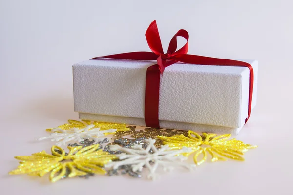 Cadeau du Nouvel An dans une boîte en carton blanc, bijoux pour sapin et bougie allumée — Photo