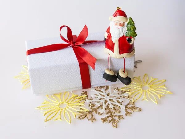 O presente de Ano Novo em uma caixa de papelão branca, jóias de um abeto e a vela ardente — Fotografia de Stock