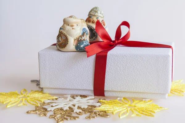 Neujahrsgeschenk in einem weißen Karton, Schmuck für einen Tannenbaum und die brennende Kerze — Stockfoto