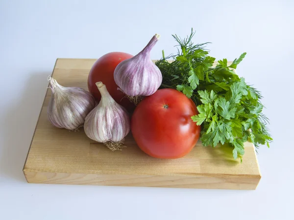 Tomatoes, garlic and greens on a table — Stock Photo, Image