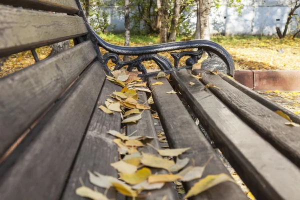 Bank mit abgefallenem Laub im Herbstpark — Stockfoto