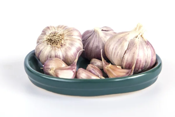 Cabezas de ajo en un platillo verde — Foto de Stock