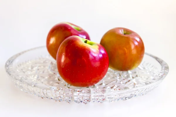 Drei große rote Äpfel auf einer Kristallschale — Stockfoto