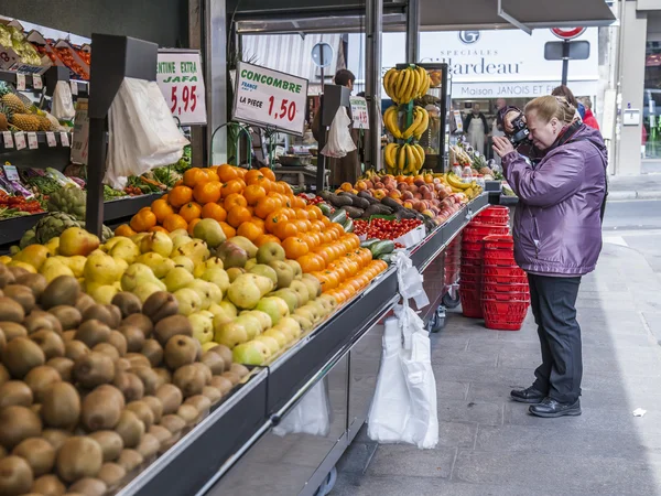 Paris, Frankrike, den 4 maj 2013. Den äldre turisten fotograferar grönsaker och frukt på en räknare av gatan marknaden — Stockfoto