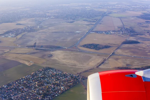 Vista da janela do avião voador em sua asa e superfície de terra — Fotografia de Stock