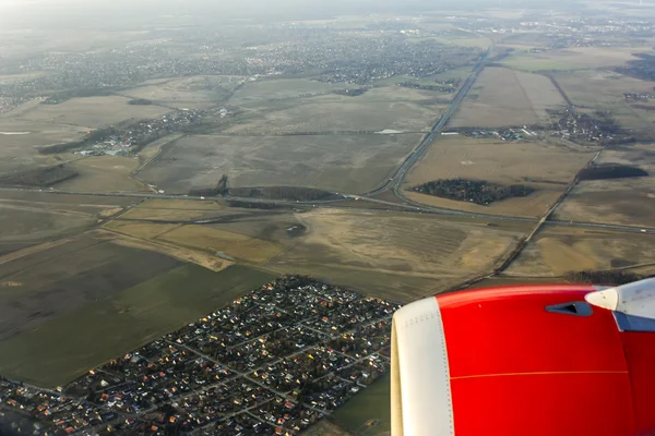 Vista da janela do avião voador em sua asa e superfície de terra — Fotografia de Stock