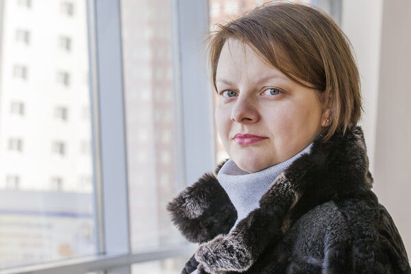 Пушкино, Россия, 10 февраля 2015 года. Молодая женщина смотрит из большого окна в торговом центре
