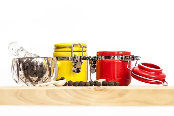 Black pepper in a transparent mortar with a pestle and multi-colored containers for spices — Stock Photo, Image