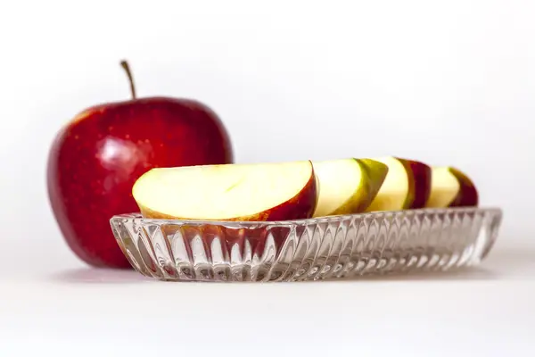 Moget rött äpple och segment av apple på en tallrik — Stockfoto