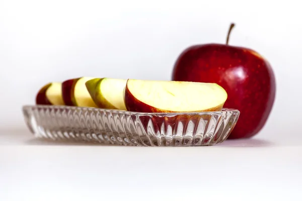 Moget rött äpple och segment av apple på en tallrik — Stockfoto