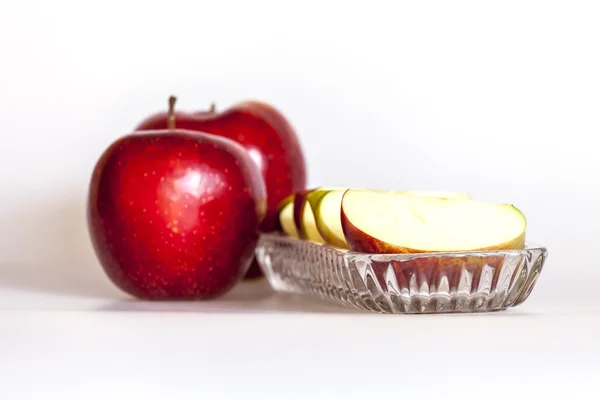 Två mogna röda äpplen och segment av apple på en tallrik — Stockfoto