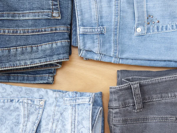 Jeans de várias cores em um balcão na loja, a visão superior — Fotografia de Stock