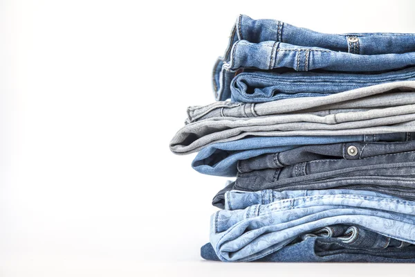 Pile of jeans of various colors on a counter in shop — Stock Photo, Image